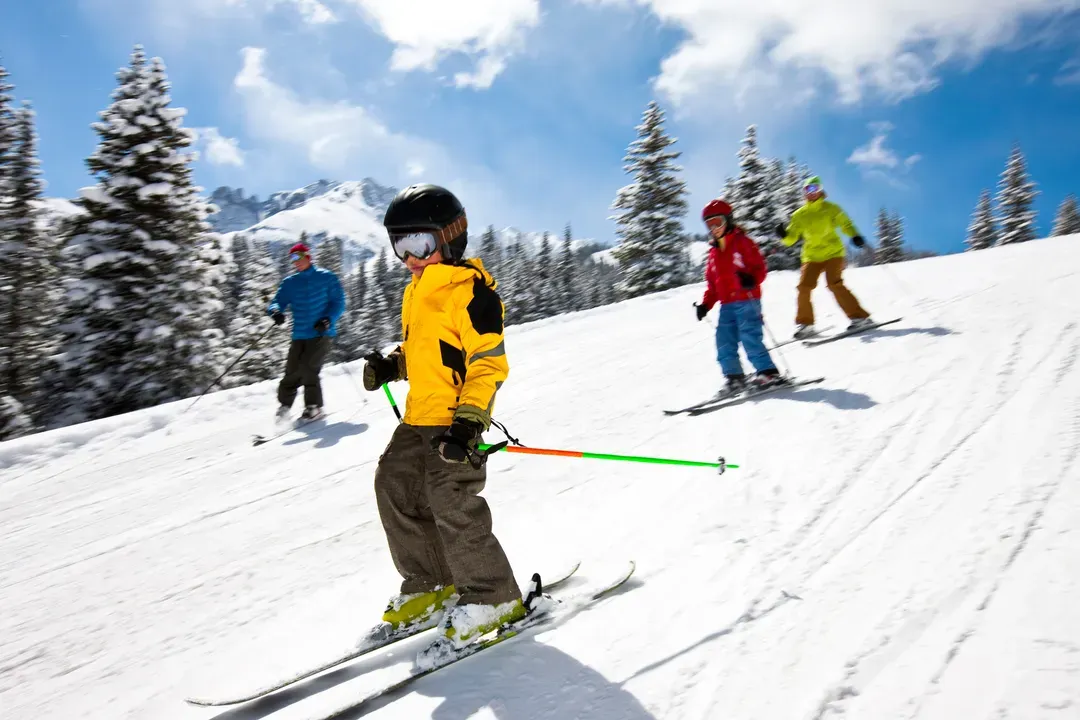 A family skiing down a groomed run on a sunny day
